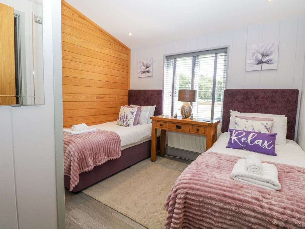 A bedroom with two beds and a wooden table at Angel Lodge - No 27 Fornham St Genevieve near Bury St Edmunds