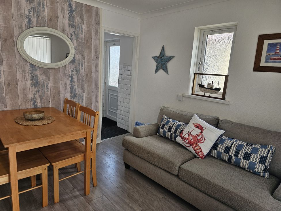 A living room with a dining table and sofa at Seahorses 