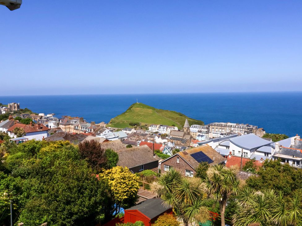 A coastal town with houses green hill and ocean in the background at Combe View in Ilfracombe