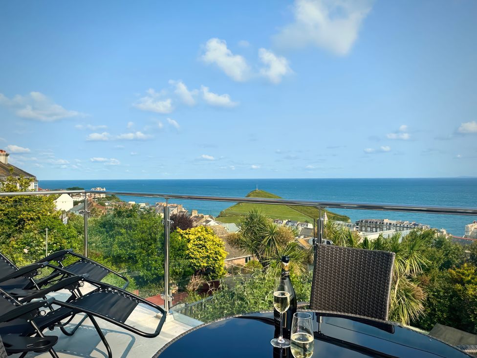 A table with drinks and chairs overlooking the sea at Combe View in Ilfracombe