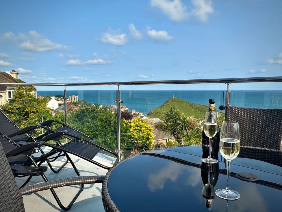 A balcony with a table and chairs overlooking the sea at Combe View Ilfracombe
