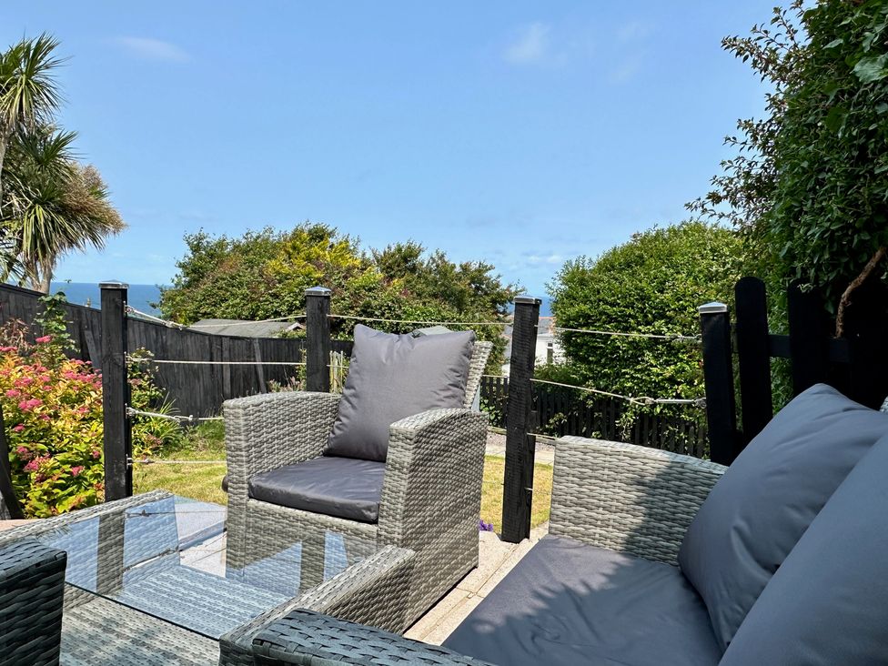 A garden with outdoor chairs and a glass table at Combe View Ilfracombe