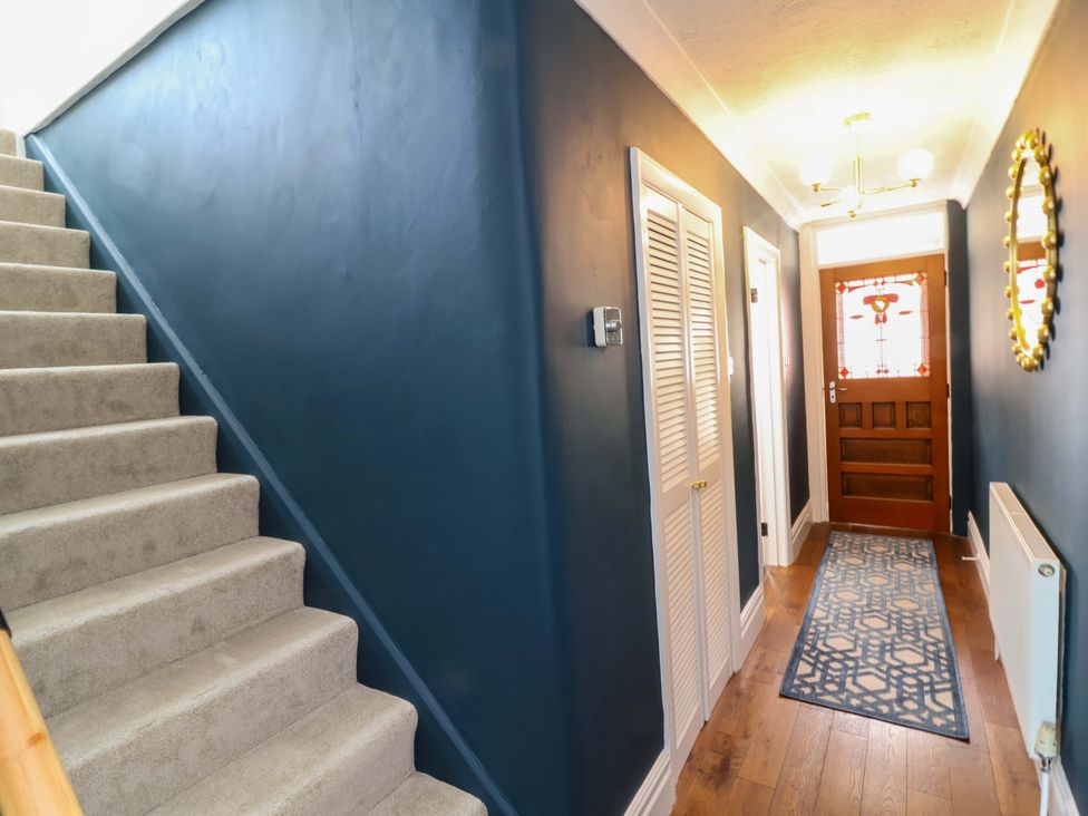 A hallway with stairs, door, and rug at Combe View in Ilfracombe