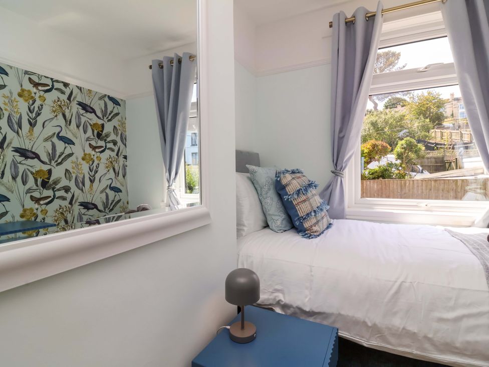 A bedroom with a bed, cushions, and a window at Combe View Ilfracombe