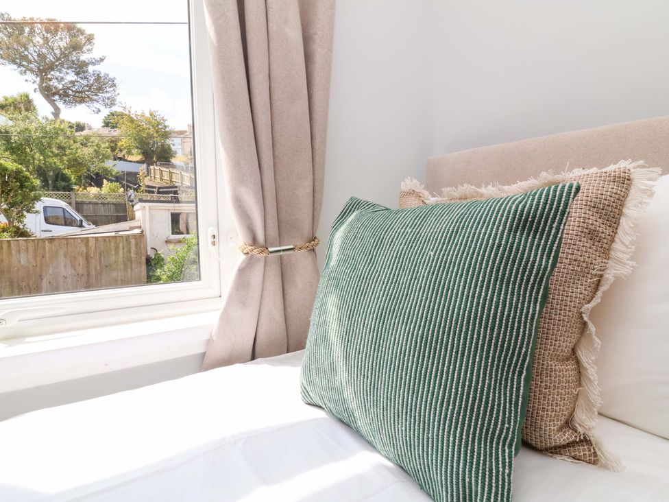 A bedroom with a window and cushions at Combe View Ilfracombe