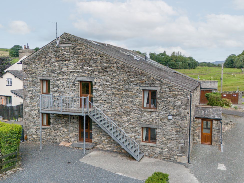 A stone building with a staircase and windows at Rockside At Pound Farm Crook near Kendal