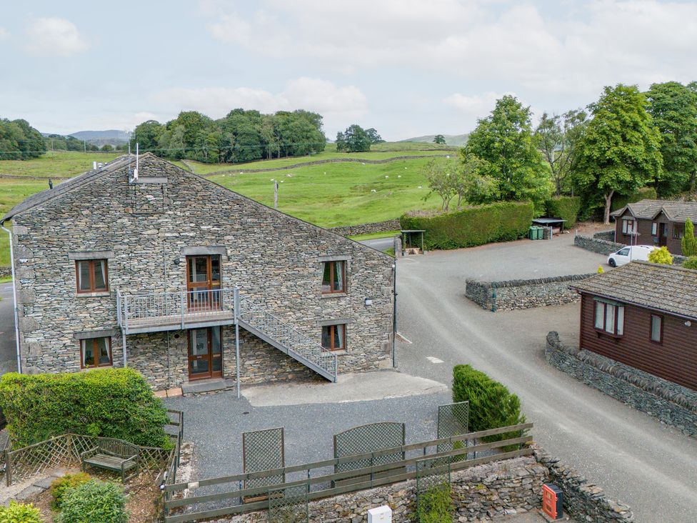 A stone building with a balcony in a grassy landscape at Bank Barn At Pound Farm Crook near Kendal
