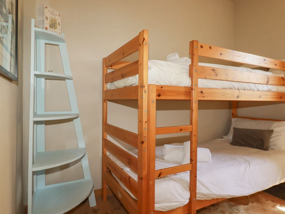 A bedroom with a bunk bed and a single bed at The Old Village Chapel in Crantock