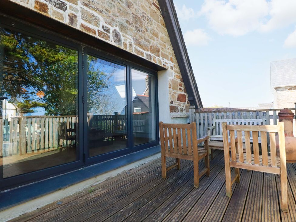 An outdoor seating area with wooden chairs and table at The Old Village Chapel in Crantock