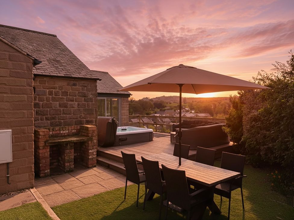 A garden with a dining table and hot tub at Barncroft in Tansley near Matlock