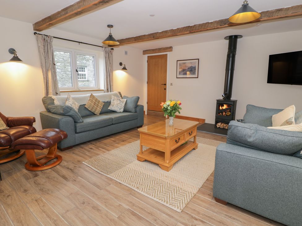 A living room with a sofa, armchair, and coffee table at Y Stabl in Cerrigydrudion