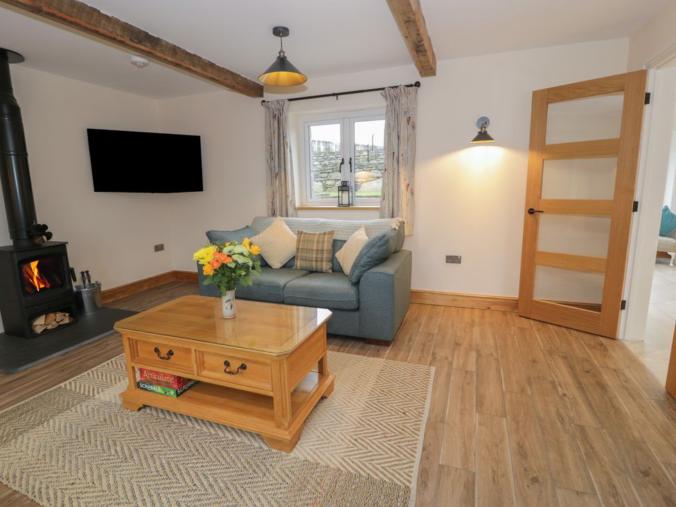 A living room with a sofa, television, and coffee table at Y Stabl in Cerrigydrudion