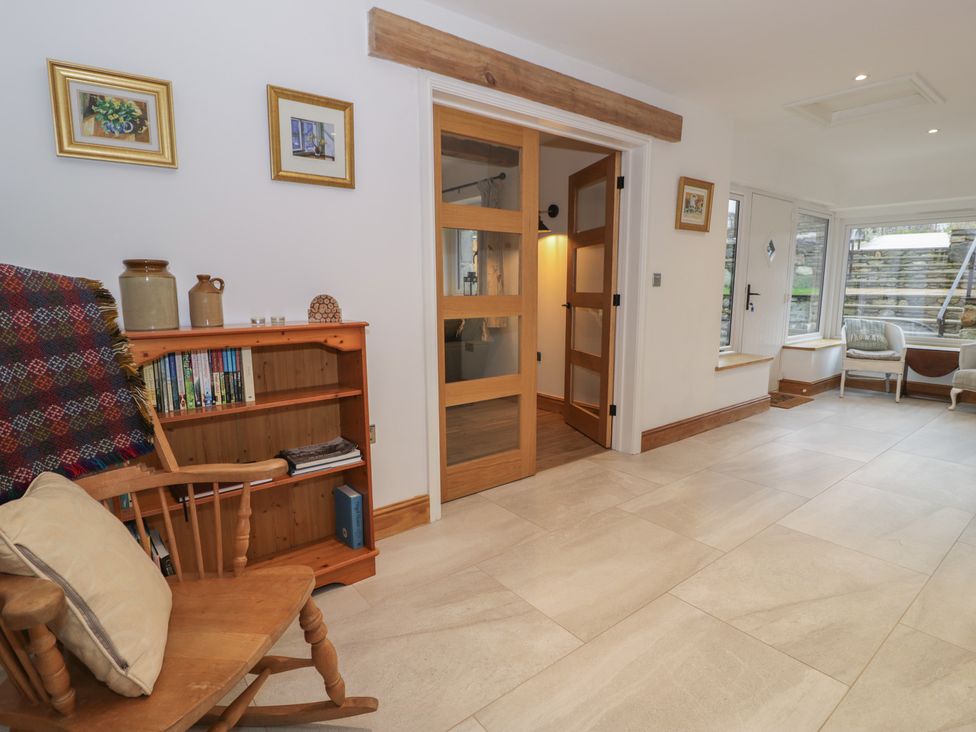 A snug with a rocking chair and bookshelves at Y Stabl in Cerrigydrudion