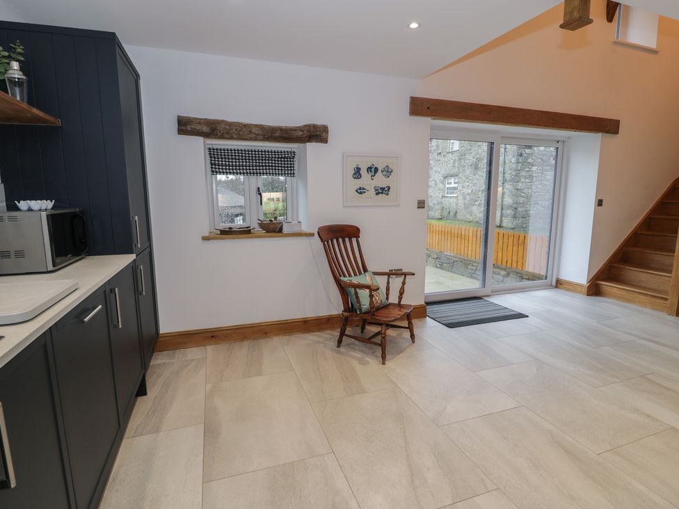 A kitchen with a rocking chair and sliding door at Y Stabl in Cerrigydrudion