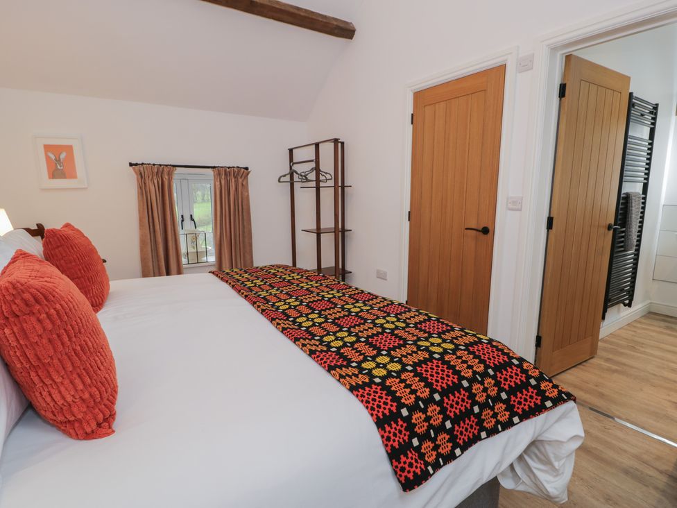 A bedroom with a bed and a clothes rack at Y Stabl in Cerrigydrudion