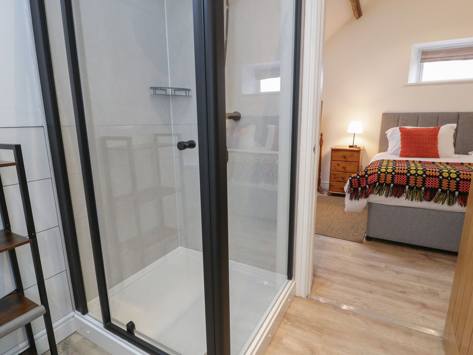A bathroom with a shower and a bedroom view at Y Stabl in Cerrigydrudion