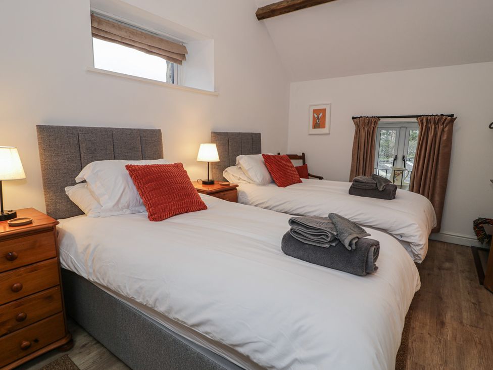 A bedroom with two single beds and a window at Y Stabl in Cerrigydrudion