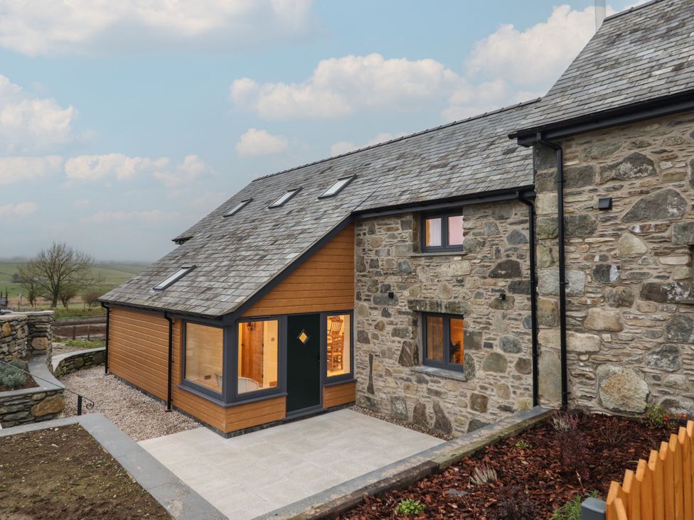 An exterior view of a house with a stone and wooden facade at Y Stabl in Cerrigydrudion