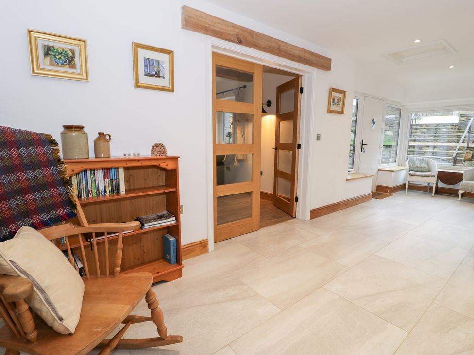 A living room with a rocking chair and bookshelf at Y Stabl in Cerrigydrudion