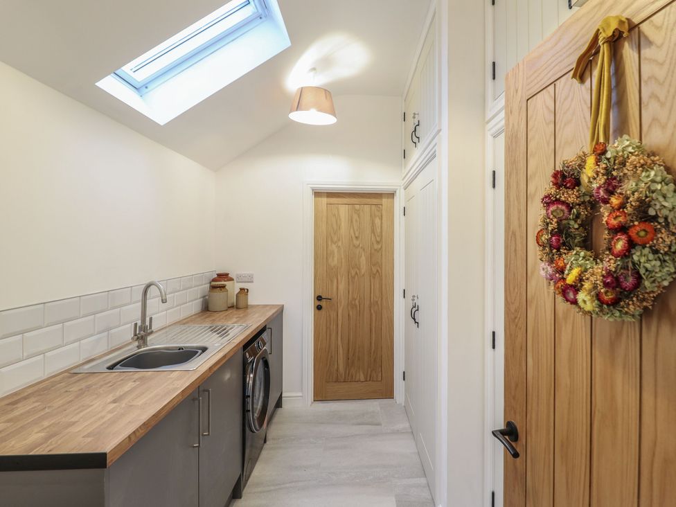 A laundry room with a sink and washing machine at Y Stabl in Cerrigydrudion
