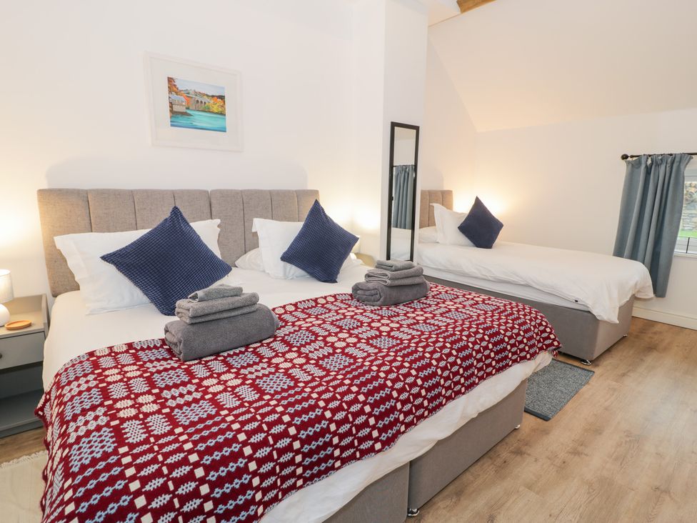 A bedroom with two beds and a mirror at Y Stabl in Cerrigydrudion