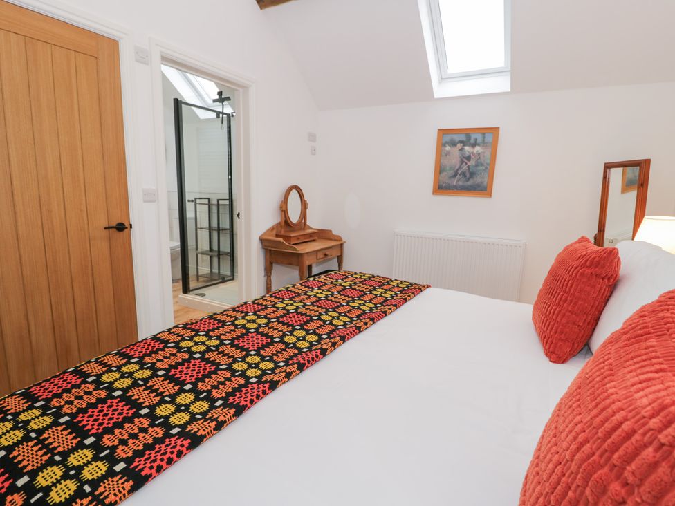 A bedroom with a bed and a mirror table at Y Stabl in Cerrigydrudion