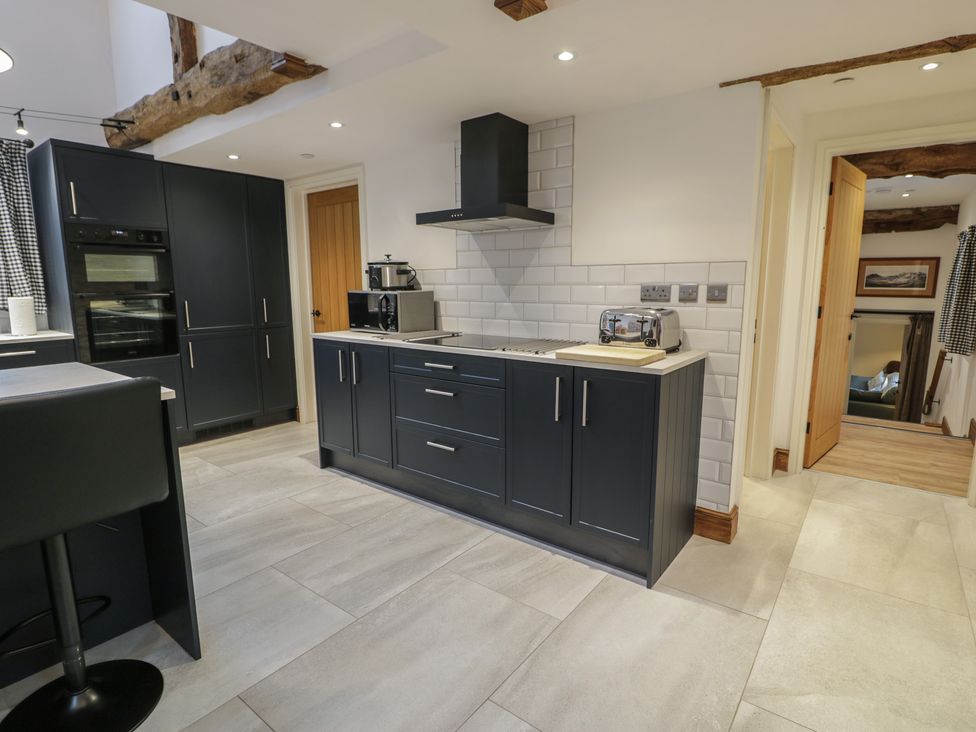 A kitchen with dark cabinets and appliances at Y Côr in Cerrigydrudion