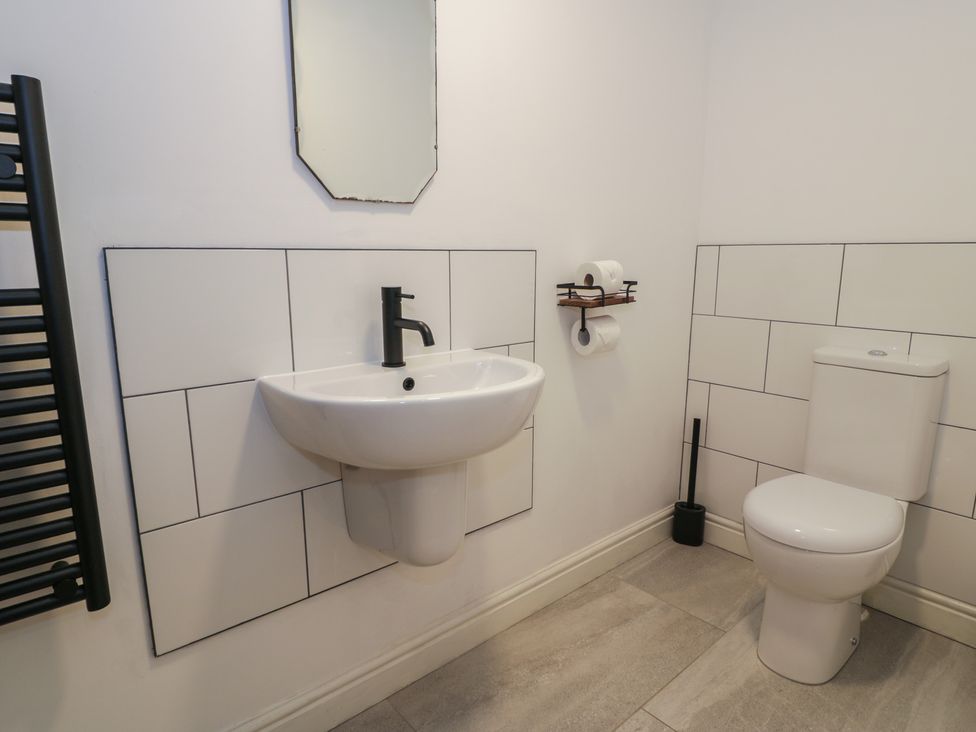 A bathroom with a sink, toilet, and mirror at Y Côr in Cerrigydrudion