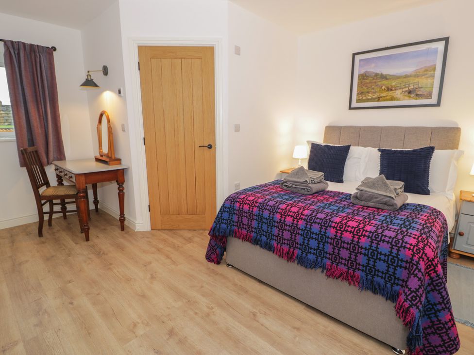 A bedroom with a bed, desk and mirror at Y Côr in Cerrigydrudion