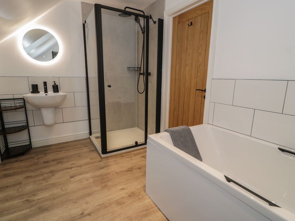 A bathroom with a shower, bathtub, and sink at Y Côr in Cerrigydrudion