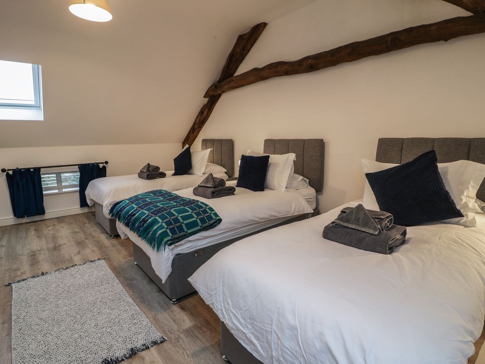A bedroom with three beds arranged and a window at Y Côr in Cerrigydrudion