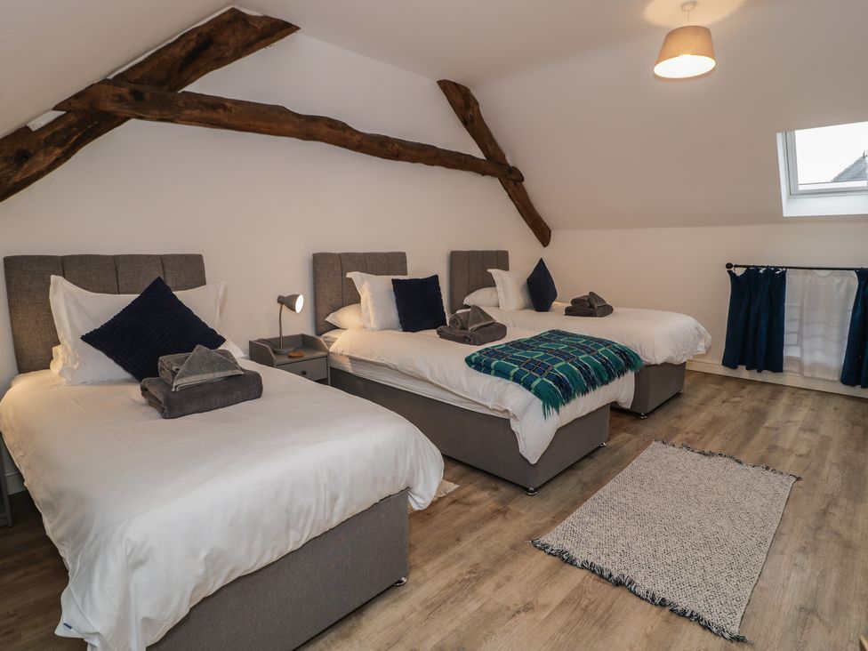 A bedroom with three beds and a window at Y Côr in Cerrigydrudion