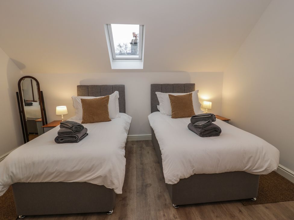 A bedroom with two single beds and a mirror at Y Côr in Cerrigydrudion