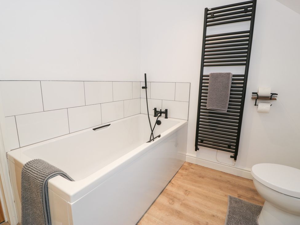 A bathroom with a bathtub and towel rack at Y Côr in Cerrigydrudion
