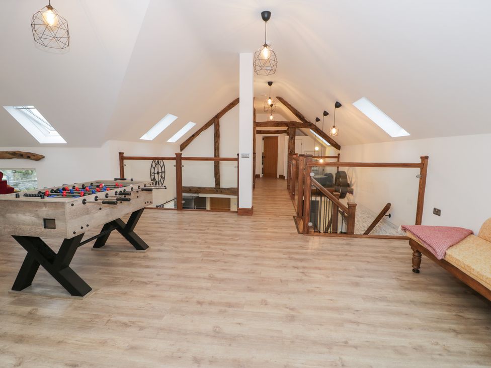 A loft area with a foosball table and wooden railing at Y Côr in Cerrigydrudion