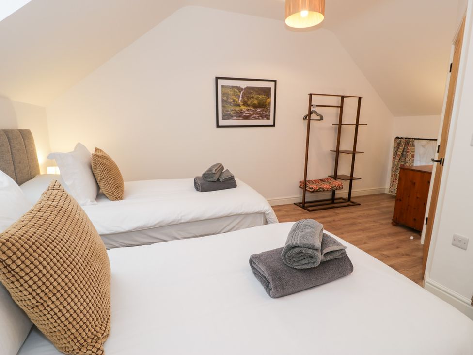 A bedroom with two beds and a clothes rack at Y Côr in Cerrigydrudion