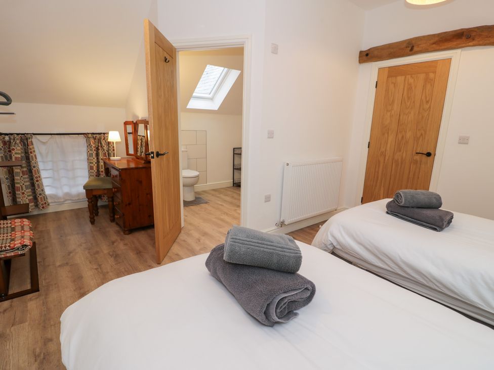 A bedroom with two beds and a doorway leading to a bathroom at Y Côr in Cerrigydrudion