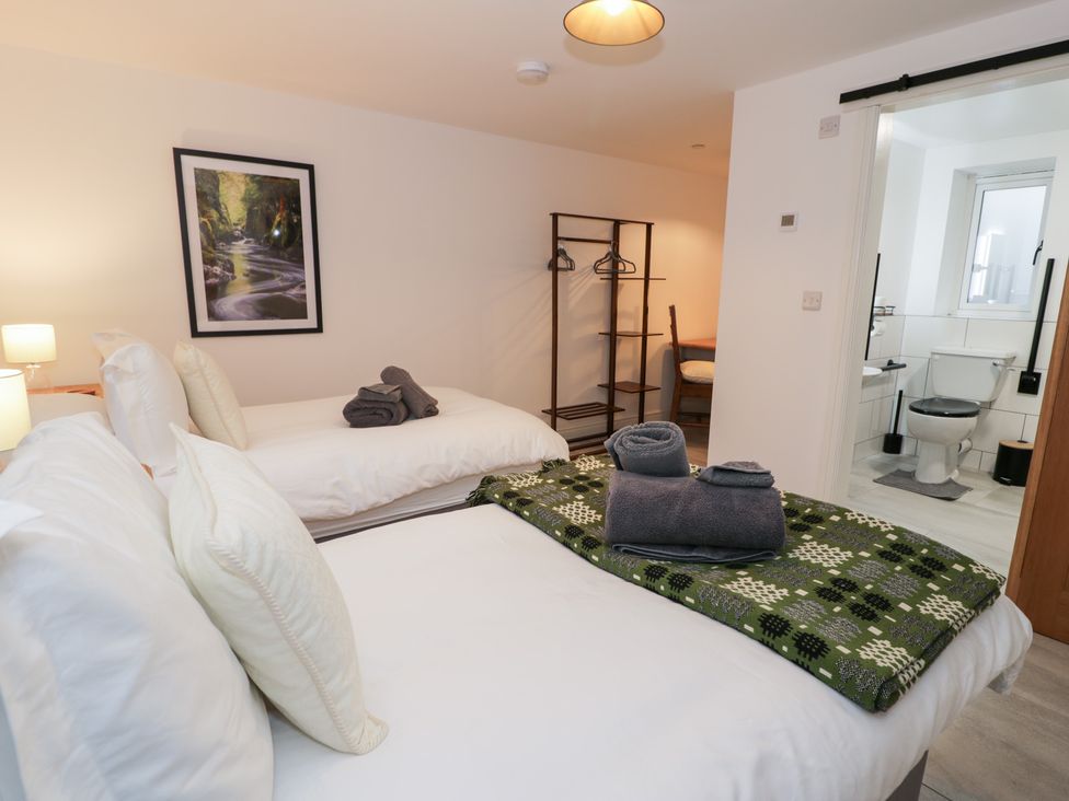A bedroom with two beds and a bathroom visible at Y Côr in Cerrigydrudion