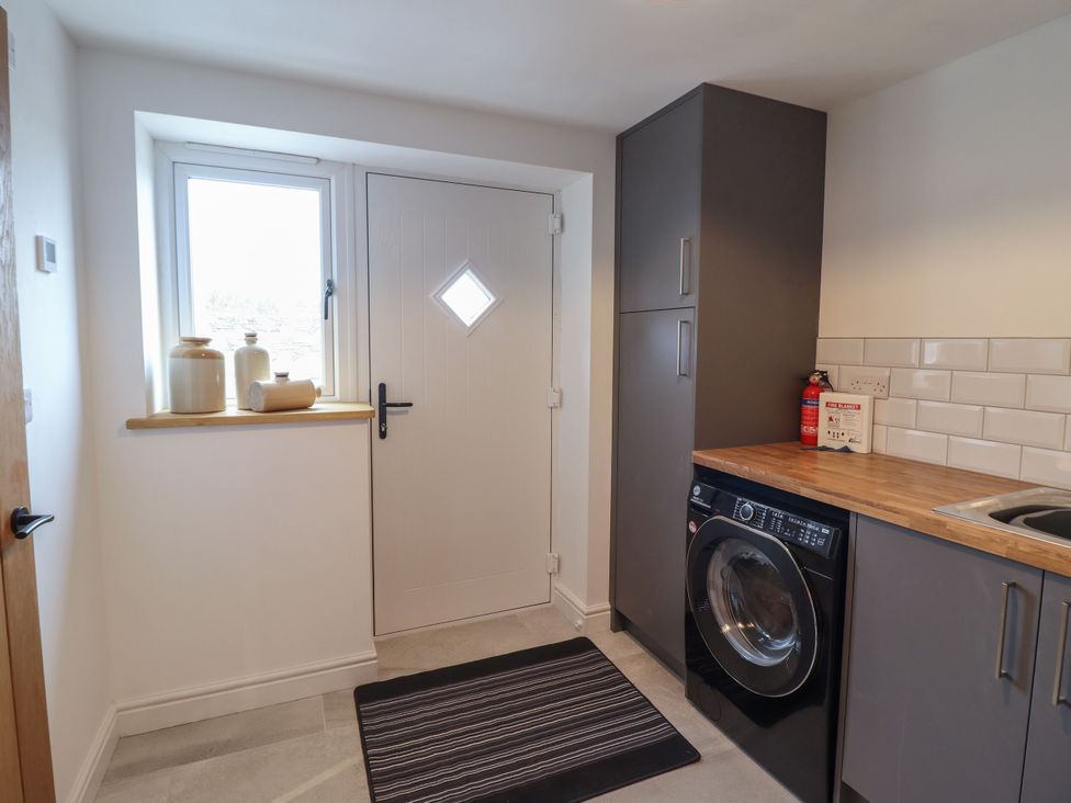 A utility room with a washing machine and window at Y Côr, Cerrigydrudion