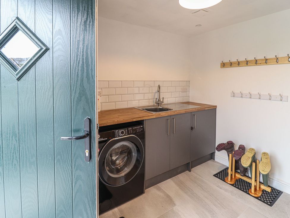 A utility room with a washer and sink at Y Côr in Cerrigydrudion