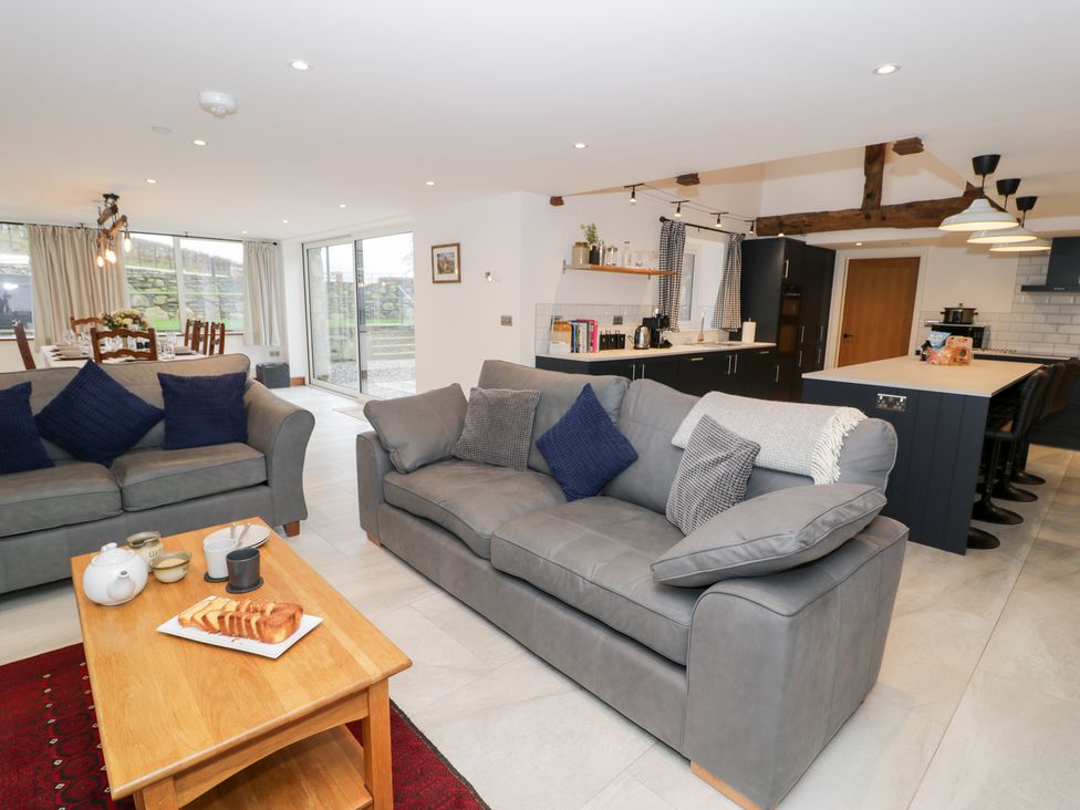 A living room with a sofa, coffee table and kitchen area at Y Côr, Cerrigydrudion