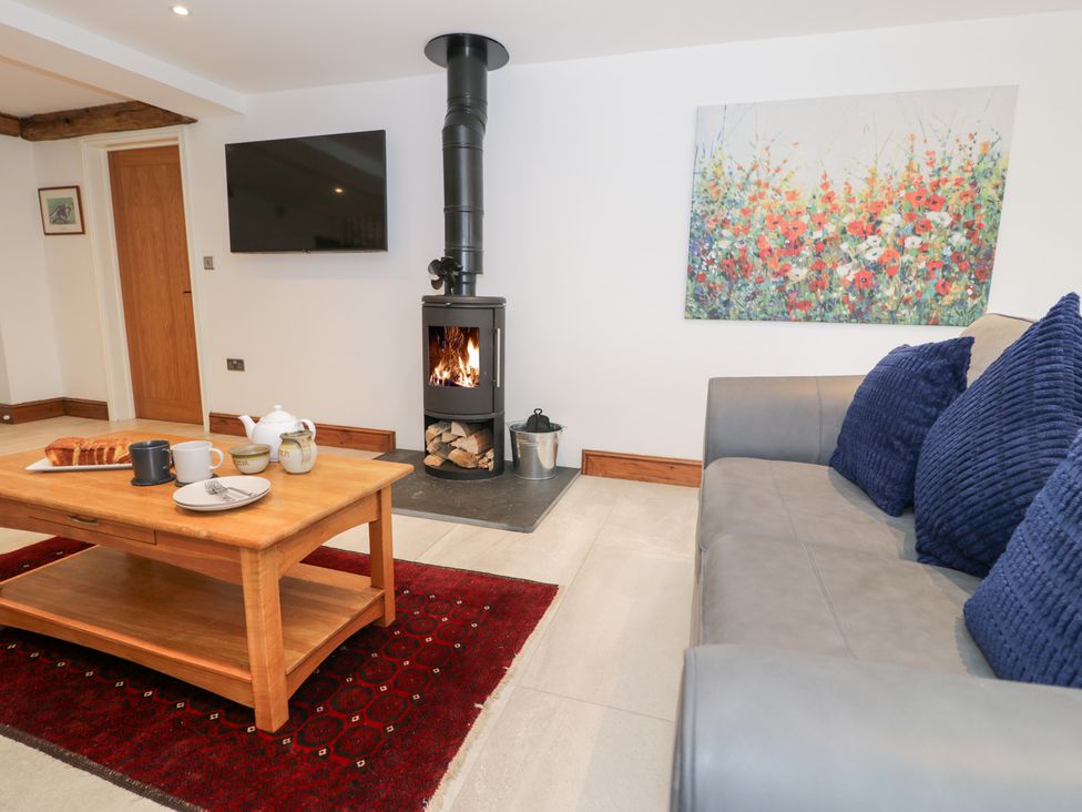 A living room with a sofa, coffee table, and fireplace at Y Côr in Cerrigydrudion