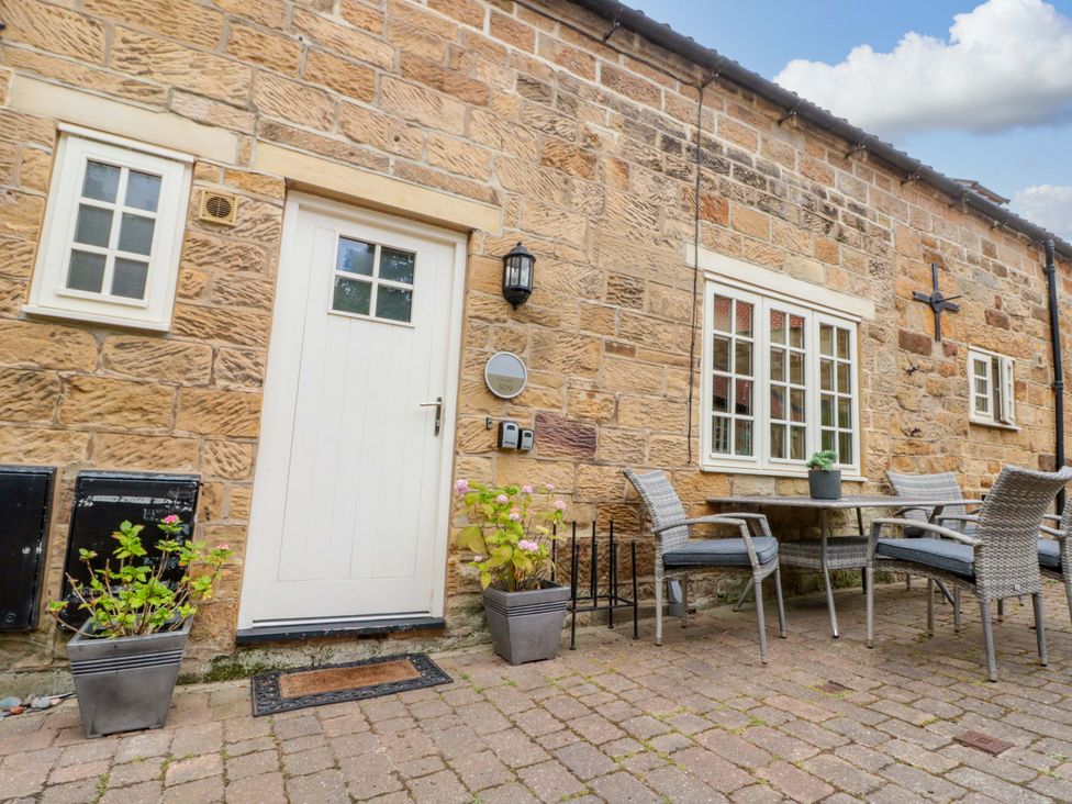 An outdoor seating area with a table and chairs at Clematis Cottage in Whitby
