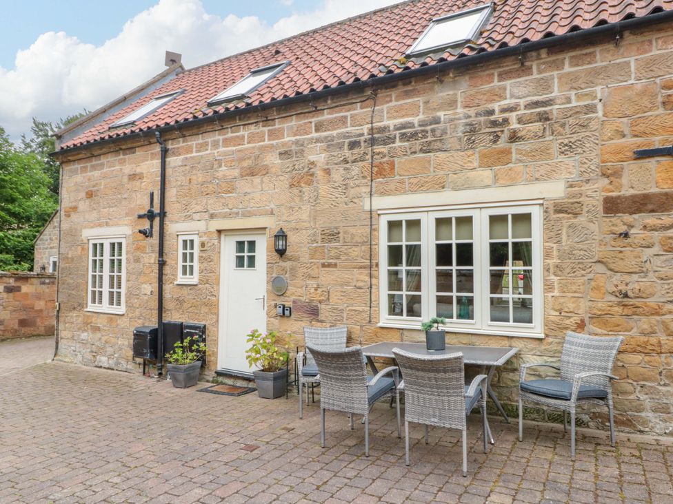 An outdoor seating area with a table and chairs at Clematis Cottage in Whitby