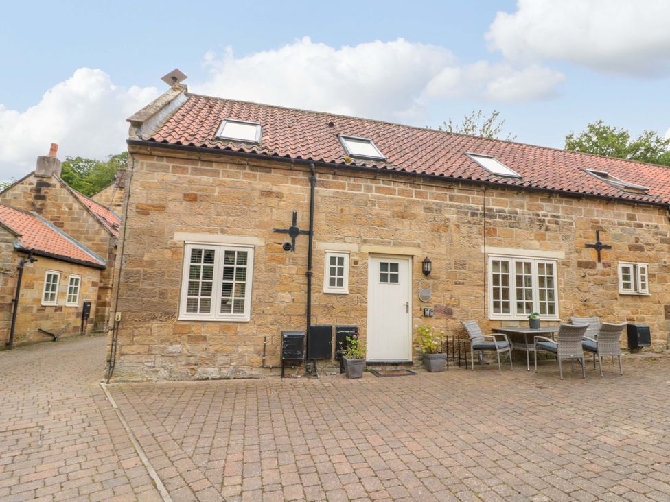 An outdoor area with seating and a stone exterior at Clematis Cottage in Whitby