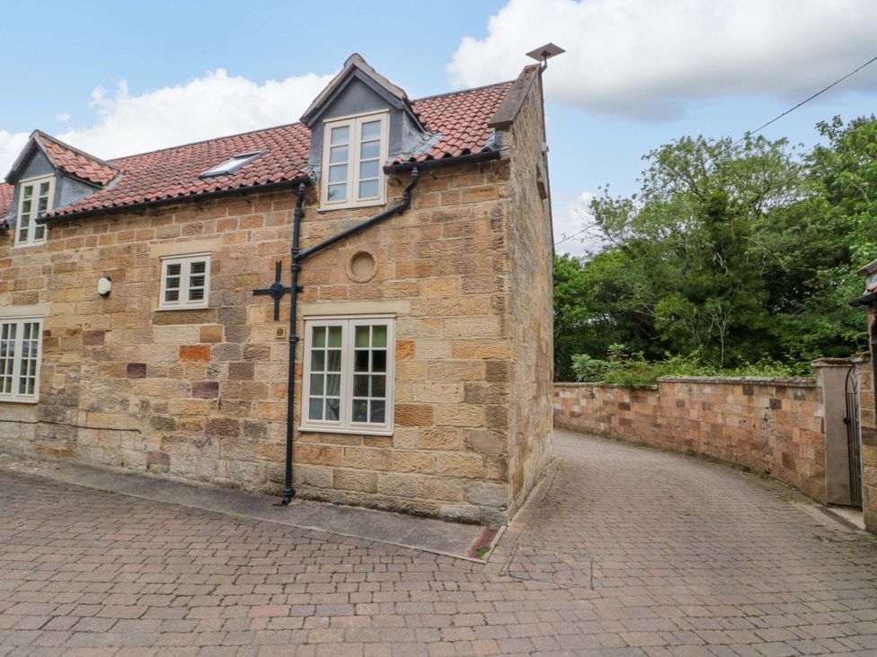 An exterior view of a stone building with windows and a pathway at Clematis Cottage in Whitby