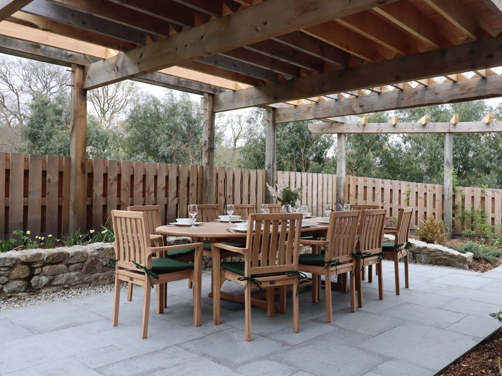 An outdoor dining area with a wooden table and chairs at Lower Moorwood, Moorwood near Bovey Tracey