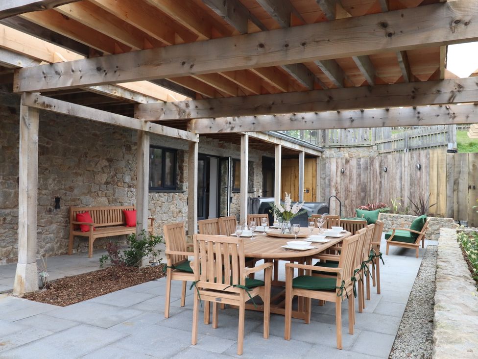 An outdoor dining area with a wooden table and chairs at Lower Moorwood in Moorwood near Bovey Tracey