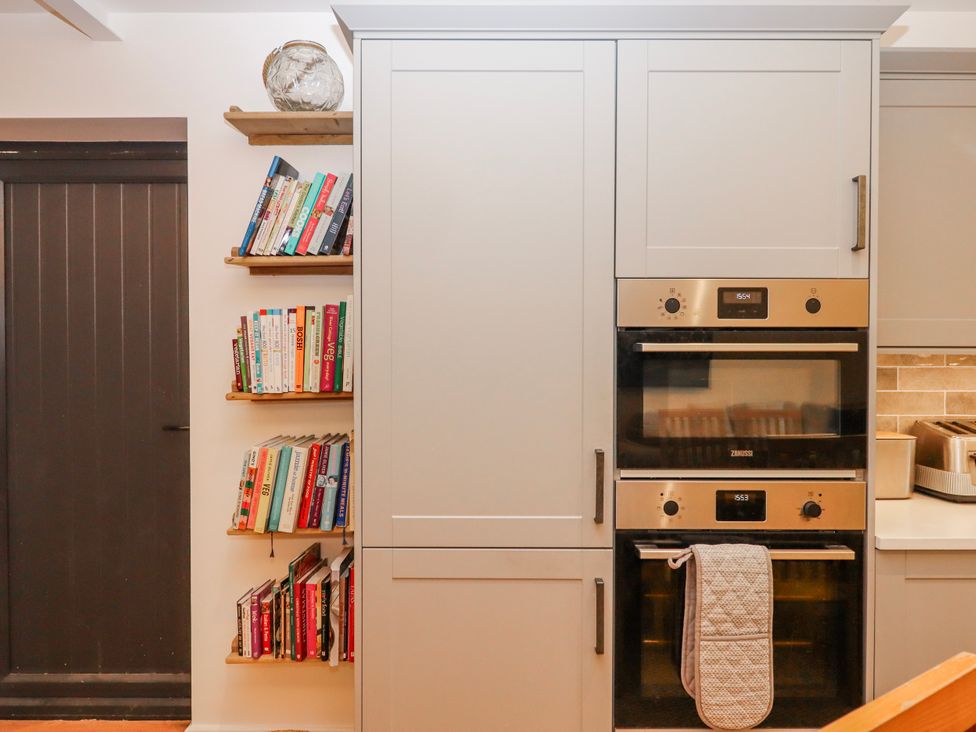 A kitchen with a bookshelf and built-in oven at Lower Moorwood Moorwood near Bovey Tracey