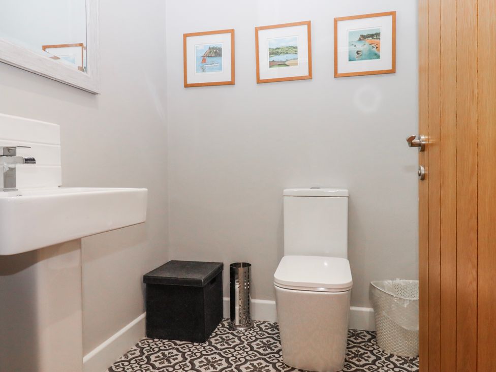 A bathroom with a toilet, sink, and framed pictures at Lower Moorwood Moorwood near Bovey Tracey